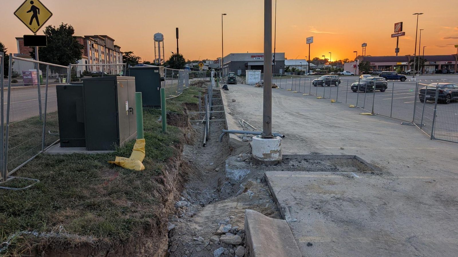 Electrical equipment and EV charging dispenser conduit and trenching in progress at a commercial retail site at dusk — the real-world site conditions EV charging diligence is built to anticipate